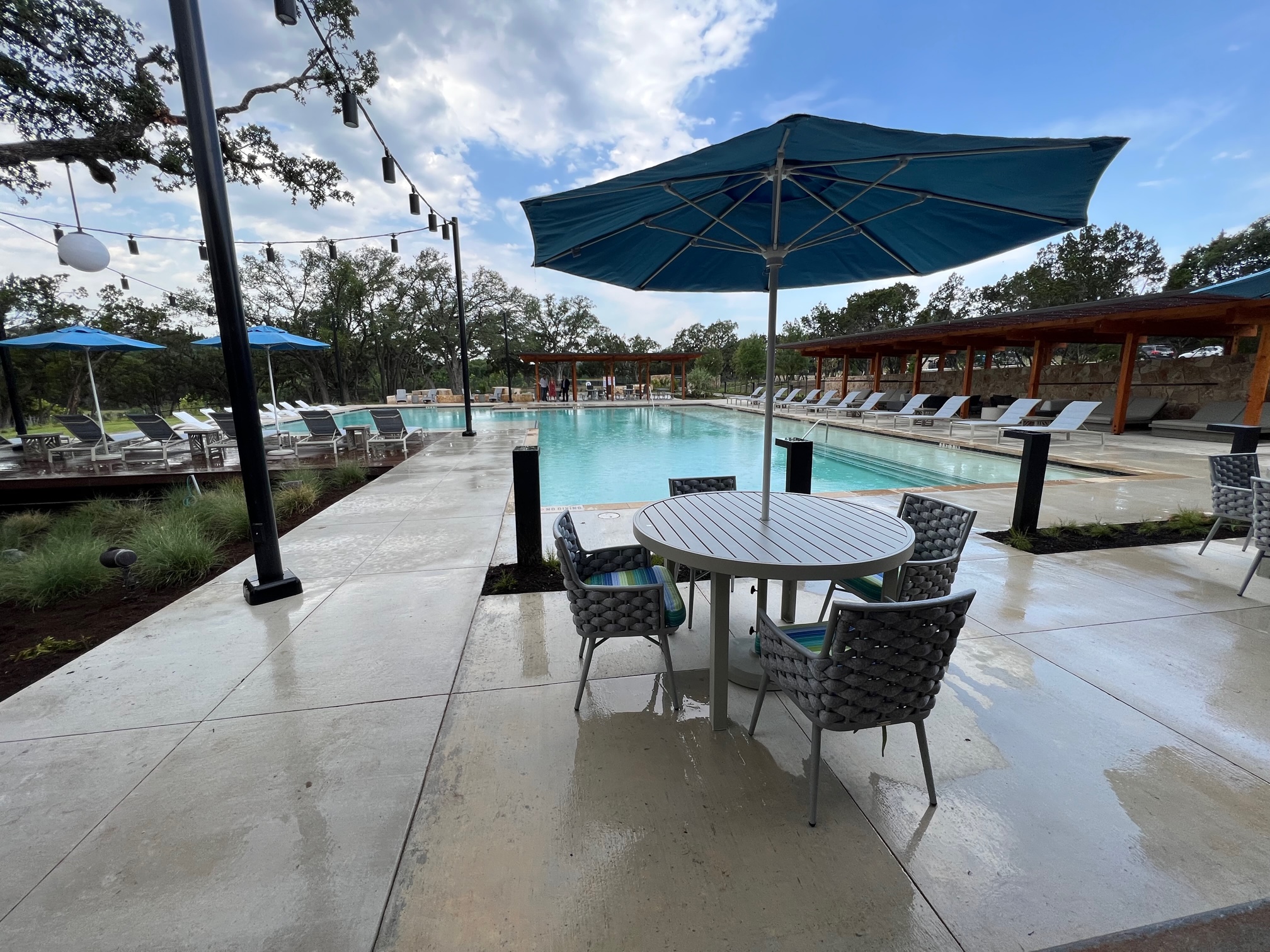 View of River Camp pool area with deck chairs, cabanas, and tables with umbrellas 
